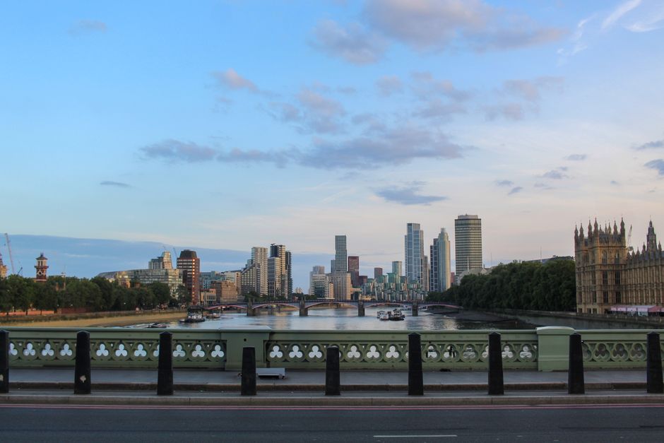 This image shows a floral arrangement featuring a bouquet of fresh flowers held by a person, set against the backdrop of Westminster Bridge and the city skyline near Westminster Bridge. The bouquet in